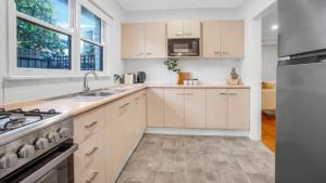 a kitchen with white cabinets and a stainless steel refrigerator at Sunnybank House with EV Charger in Cheltenham +6 photos