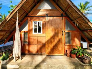a wooden door of a house with potted plants at Duon Baler - Seconds from Sabang beach, your peaceful escape in Baler