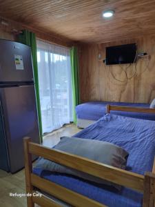 una camera con 2 letti, un frigorifero e una TV di Refugio de Caty a Bahía Mansa