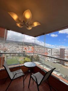 een balkon met een tafel en stoelen voor een groot raam bij Luxury, Comfort central área in Pasto