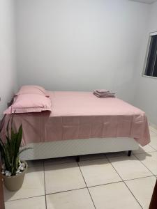 a bed with pink sheets and a plant in a room at Apartamento Sabrina in Curitiba +6 photos