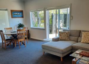 a living room with a couch and a table and chairs at Villa One on Fitzherbert in Palmerston North