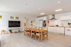 eine Küche und ein Esszimmer mit einem Holztisch und Stühlen in der Unterkunft Luxury Private House near Beach in Costa da Caparica