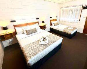 a hotel room with two beds and two tables at Tartan Motel, Yea in Yea