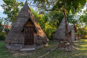a small house with a thatched roof next to a tree at The Last Resort in Don Det