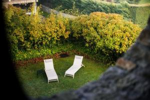 Zwei weiße Stühle stehen im Gras neben einem Busch. in der Unterkunft Hotel Boutique Barosse Jaca in Jaca
