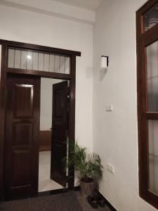 a hallway with a door and a plant in front of it at Cinnamon Shade by Achievers in Negombo +3 photos