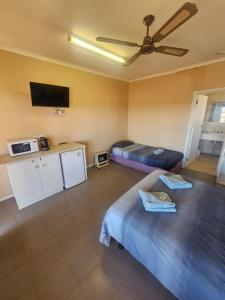 una camera con due letti e una TV a schermo piatto di Cadney Park Accommodation a Coober Pedy