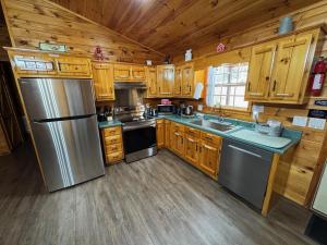 a kitchen with wooden cabinets and a stainless steel refrigerator at Hillside Hideaway Cabin in Blairsville