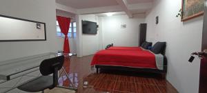 een slaapkamer met een bed met een rode sprei bij La Patrona Hostal in Santa Cruz Xoxocotlán