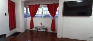 een kamer met rode gordijnen, een tafel en een tv bij La Patrona Hostal in Santa Cruz Xoxocotlán