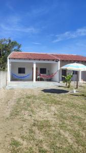 een wit huis met een rood dak en een paraplu bij Casa Nova - Pontal do Paraná in Pontal do Paraná