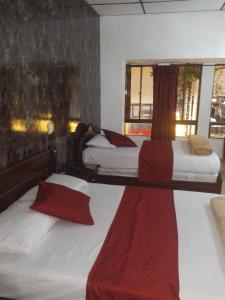 zwei Betten in einem Hotelzimmer mit roten Kissen in der Unterkunft Hotel Ejecutivo in Pereira