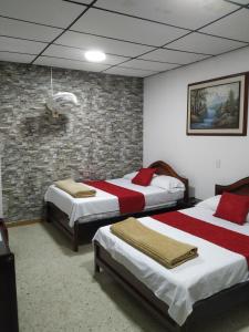 ein Schlafzimmer mit zwei Betten und einer Ziegelwand in der Unterkunft Hotel Ejecutivo in Pereira