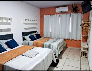 巴雷里尼亚斯Hospedagem Aconchego Do Lar的橙色墙壁的房间里有两张床