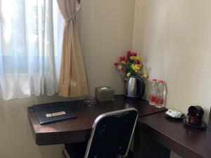 een bureau met een laptop en een vaas met bloemen bij Grand Bydiel in Lanjang