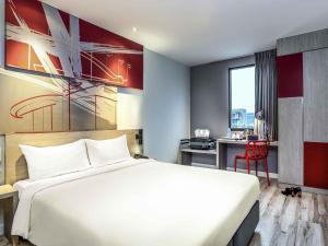 a hotel room with a white bed and a desk at ibis Bangkok IMPACT in Nonthaburi