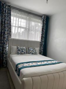 een slaapkamer met een groot bed en een raam bij Grey Nest Grey point 303 in Kericho