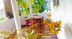 a table and chairs on a porch with plants at White Sky in Hikkaduwa
