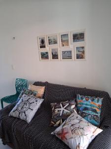 a couch with pillows and pictures on a wall at Apartamentos e Casas em Barra do Cunhaú in Canguaretama +45 photos