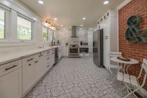 une cuisine avec des placards blancs et un mur en briques dans l'établissement Southern Pines Gem with 2 Master-King Suites, à Southern Pines