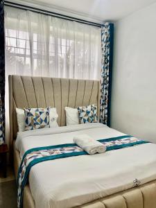 een slaapkamer met een groot bed met een groot raam bij Grey Nest Grey point 303 in Kericho +4 foto's