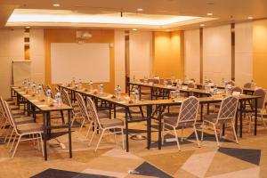 una grande sala conferenze con tavoli e sedie lunghi di All Sedayu Hotel Kelapa Gading a Giacarta