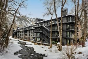 an apartment building in the snow next to a river at Chateau Roaring Fork Unit 37, Spacious Condo, Close to Downtown. Pool, Hot Tub, Fitness Center in Aspen