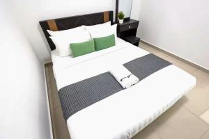 a bedroom with a bed with white sheets and green pillows at NOVO 8 Residence Melaka in Malacca +99 photos