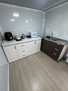een kleine keuken met witte kasten en een magnetron bij Residencial Manhattan in Passo Fundo