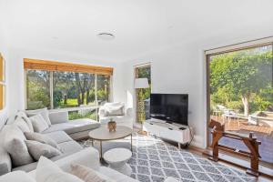 a living room with white furniture and a large window at Point Break in Bawley Point