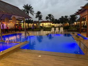 a large pool with chairs and blue water at مزرعة منتجع الامراء in Baghdād