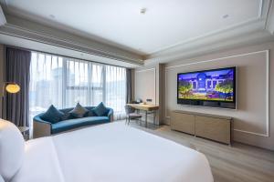 a hotel room with a bed and a flat screen tv at Mercure Tianshui Downtown in Tianshui