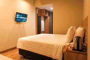 une chambre d'hôtel avec un lit et une télévision à écran plat dans l'établissement Grand Damai Kostel Exclusive, à Ngaglik