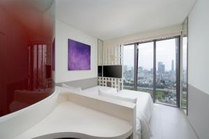 een slaapkamer met witte meubels en een groot raam bij Wink Danang Riverside, Unscripted by Hyatt in Da Nang