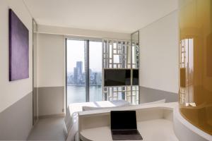 een slaapkamer met een laptop op een bed met een raam bij Wink Danang Riverside, Unscripted by Hyatt in Da Nang