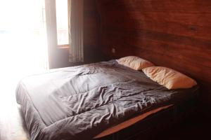 an unmade bed in a bedroom with a wooden wall at North Pagai Bungalows in Pulau Silabusabeu