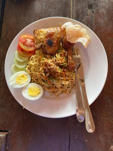 a plate of food with noodles and eggs on a table at North Pagai Bungalows in Pulau Silabusabeu