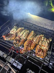a bunch of food cooking on a grill at North Pagai Bungalows in Pulau Silabusabeu