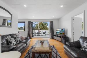 a living room with two leather couches and a coffee table at Beach Haven - Papamoa Beach Escape in Papamoa