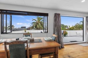 a dining room with a table and a large window at Beach Haven - Papamoa Beach Escape in Papamoa