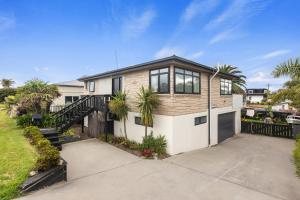 a house with a fence and a driveway at Beach Haven - Papamoa Beach Escape in Papamoa