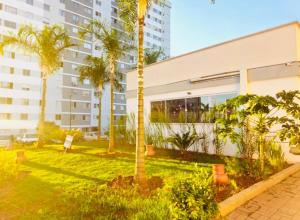 a building with palm trees in front of it at Apto Confortável - Supermercado Bahamas ao lado in Uberaba
