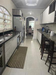 a kitchen with a refrigerator and a table with chairs at Bela casa com piscina in Mongaguá