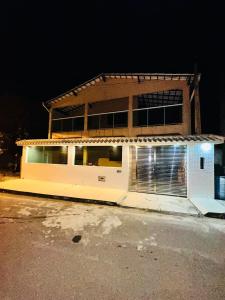 a large white building with a garage at night at Casa de praia in Itapemirim +4 photos