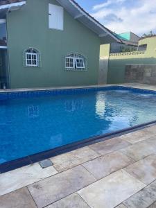 a blue swimming pool in front of a house at Bela casa com piscina in Mongaguá