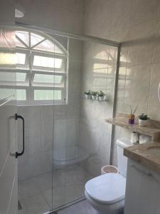 a bathroom with a toilet and a glass shower at Bela casa com piscina in Mongaguá +14 photos