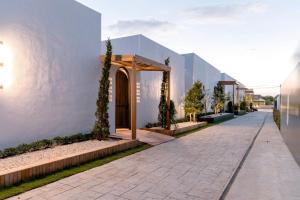 a street with a white building and a sidewalk at Merry Holmes Resort Hatyai in Ban Tha Sae