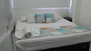 een wit bed met kussens en een deken erop bij Boutique Real PRB in Barrancabermeja