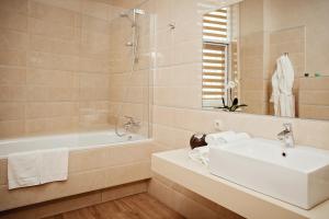 a white bath tub sitting next to a white sink at Hotel Versailles in Lutsk